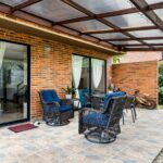 Inviting brick patio with wicker chairs and plants, perfect for relaxation.