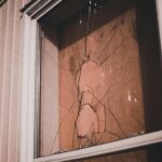 Detailed view of a cracked window pane at night, highlighting textures and reflections.