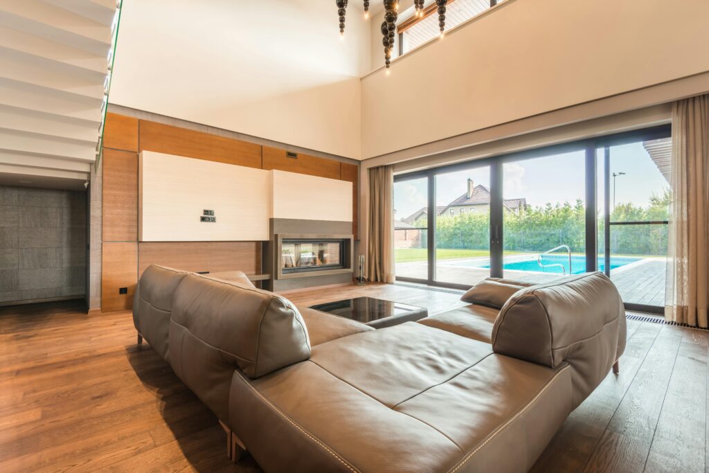 pexels-photo-8134818-8134818 Spacious modern living room featuring a leather sofa and glass doors overlooking a swimming pool.
